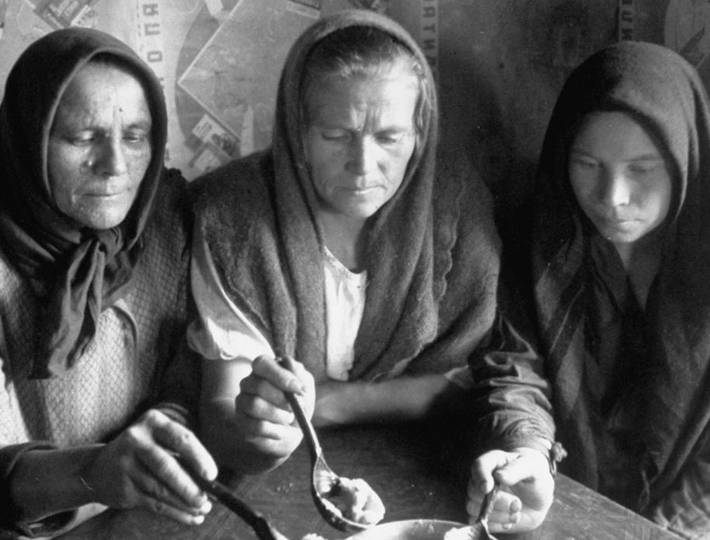  Три женщины едят кашу из одной плошки деревянными ложками